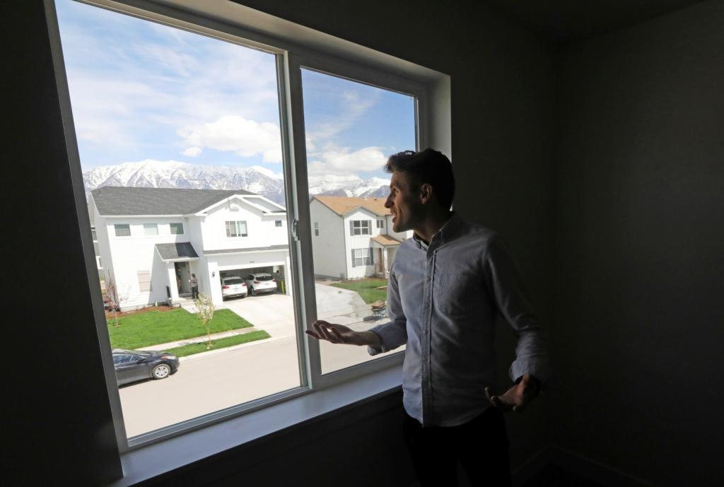 Andy Proctor looks through the window of his new home in Vineyard, Utah.  As wages have stagnated, the costs of essentials like housing and education